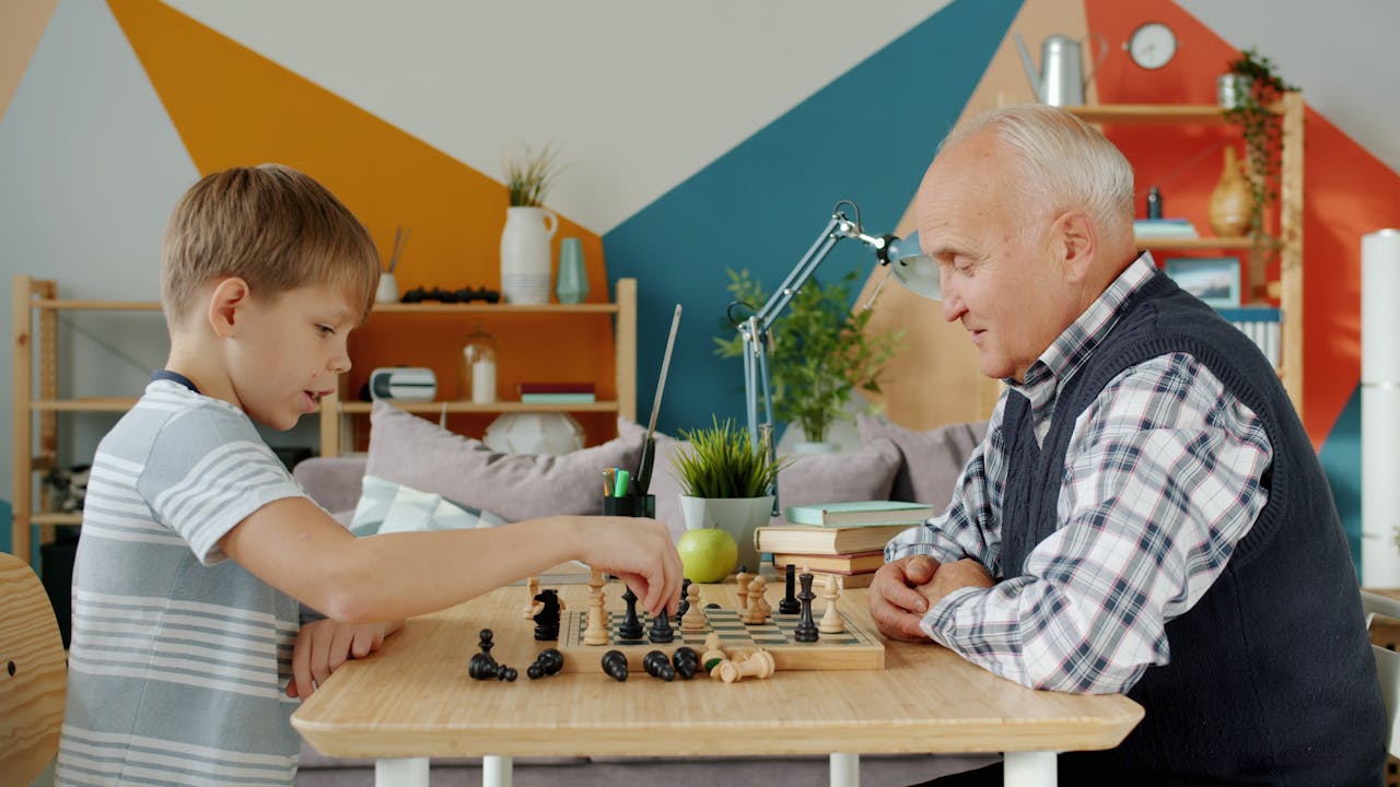 An elderly man and a boy enjoy an engaging game of chess, fostering connection.